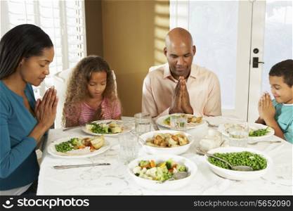 Family Saying Grace Before Meal At Home