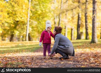 family, season and people concept - happy mother and little daughter at autumn park. happy mother and little daughter at autumn park. happy mother and little daughter at autumn park