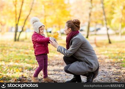 family, season and people concept - happy mother and little daughter with autumn leaves at park. happy family with autumn leaves at park. happy family with autumn leaves at park