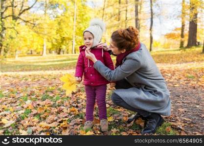 family, season and people concept - happy mother and little daughter with autumn leaves at park. happy family with autumn leaves at park