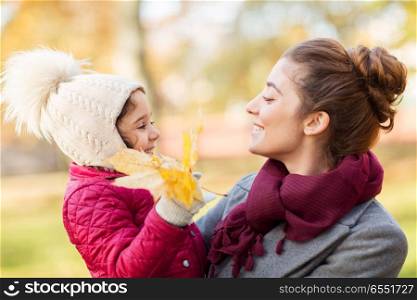 family, season and people concept - happy mother and little daughter with autumn maple leaves. mother and little daughter with autumn leaves. mother and little daughter with autumn leaves