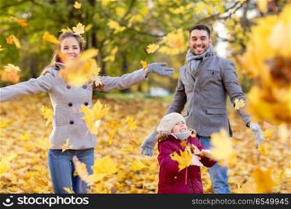 family, season and people concept - happy mother, father and little daughter playing with autumn leaves at park. happy family playing with autumn leaves at park. happy family playing with autumn leaves at park