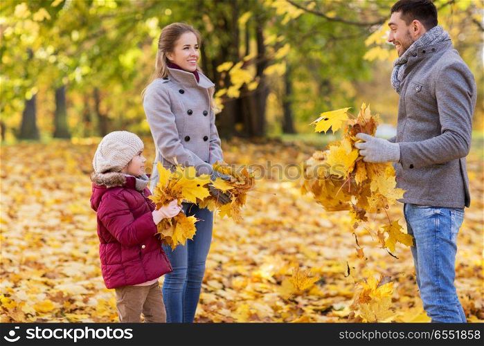 family, season and people concept - happy mother, father and little daughter playing with autumn leaves at park. happy family playing with autumn leaves at park. happy family playing with autumn leaves at park