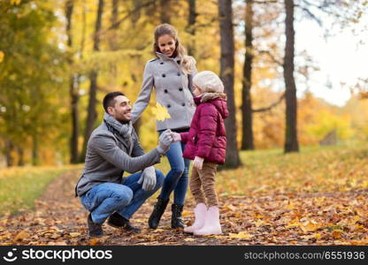 family, season and people concept - happy mother, father and little daughter with maple leaf at autumn park. happy family with maple leaf at autumn park. happy family with maple leaf at autumn park