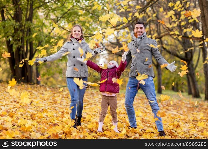 family, season and people concept - happy mother, father and little daughter playing with autumn leaves at park. happy family playing with autumn leaves at park