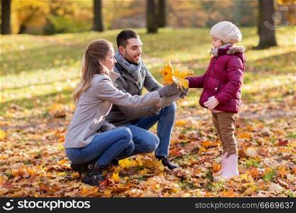 family, season and people concept - happy mother, father and little daughter with maple leaves at autumn park. happy family with maple leaves at autumn park. happy family with maple leaves at autumn park