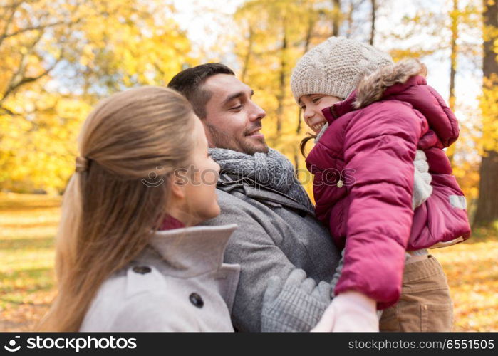 family, season and people concept - happy mother, father and little daughter at autumn park. happy family at autumn park. happy family at autumn park