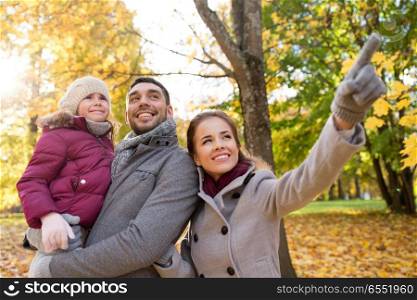 family, season and people concept - happy mother, father and little daughter at autumn park. happy family at autumn park. happy family at autumn park