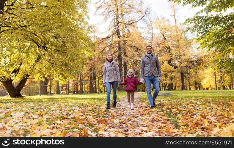 family, season and people concept - happy mother, father and little daughter walking at autumn park. happy family walking at autumn park. happy family walking at autumn park