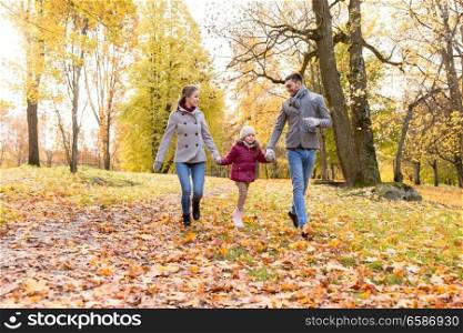 family, season and people concept - happy mother, father and little daughter walking at autumn park. happy family walking at autumn park