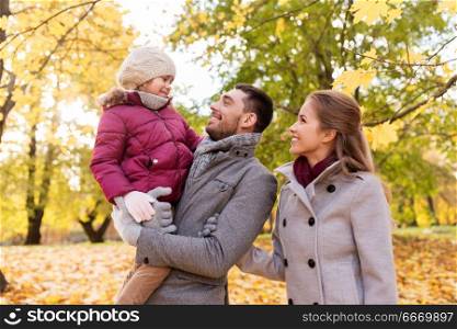 family, season and people concept - happy mother, father and little daughter walking at autumn park. happy family walking at autumn park. happy family walking at autumn park