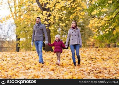 family, season and people concept - happy mother, father and little daughter walking at autumn park. happy family walking at autumn park
