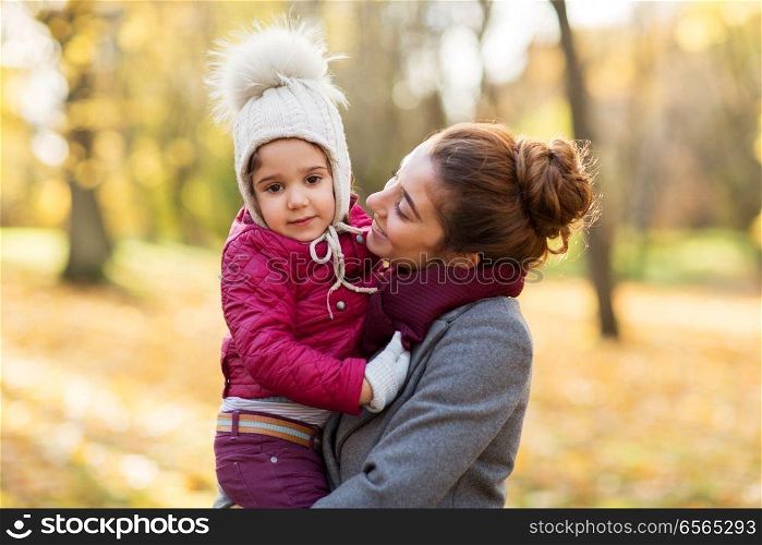 family, season and people concept - happy mother holding little daughter at autumn park. happy mother with little daughter at autumn park