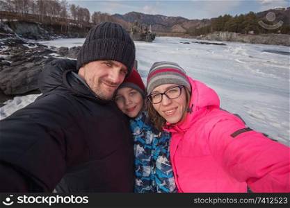 Family selfie at winter journey. Mother, father and son taking selfie photo in forest at beauty sunny winter day, in Altai mountains. Travel vacation concept.. Family selfie at winter journey.