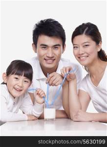 Family sharing a glass of milk, studio shot