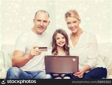 family, shopping, technology and people concept - happy family with laptop computer and credit card over snowflakes background