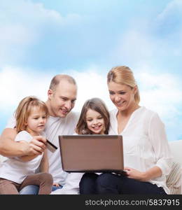 family, shopping, technology and people - happy family with laptop computer and credit card over blue sky background