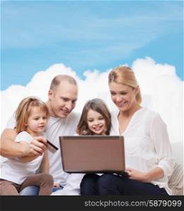 family, shopping, technology and people - happy family with laptop computer and credit card over blue sky and white cloud background