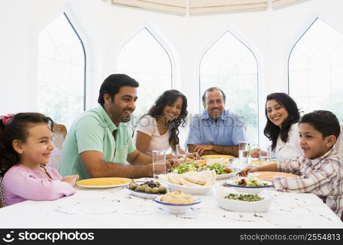 Family sitting at dinner table smiling (high key)