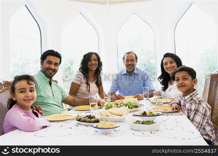 Family sitting at dinner table smiling (high key)
