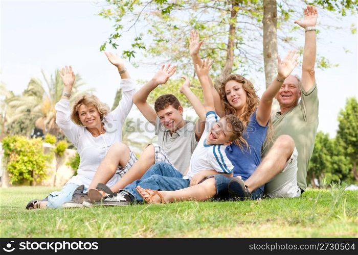 family sitting in a park and waving hands