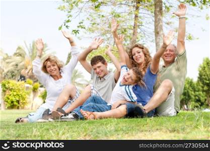 family sitting in a park and waving hands
