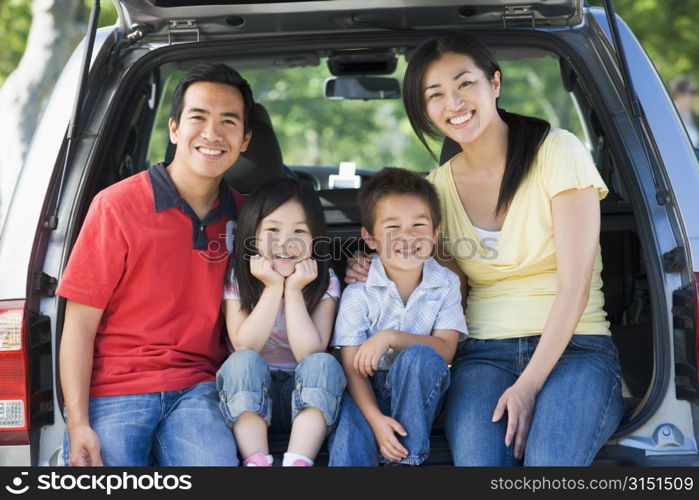 Family sitting in back of van smiling