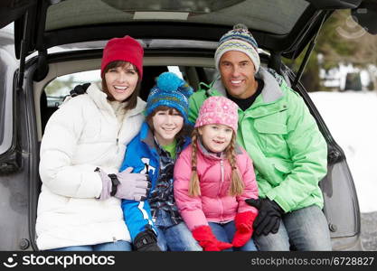 Family Sitting In Boot Of Car Wearing Winter Clothes