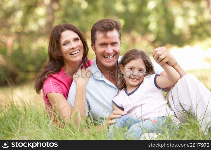 Family Sitting In Long Grass In Park