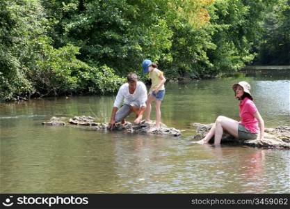 Family sitting in river in summer