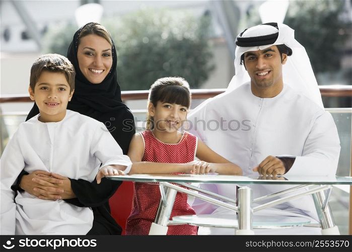 Family sitting indoors at table smiling (selective focus)