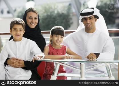 Family sitting indoors at table smiling (selective focus)