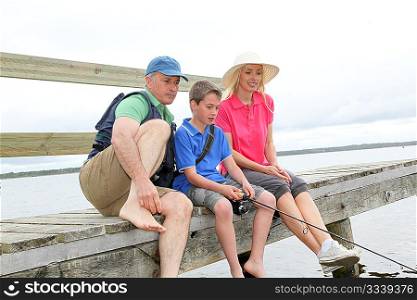 Family sitting on a pontoon with kid fishing