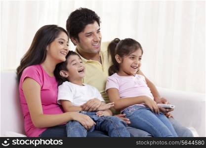 Family sitting on a sofa watching TV together
