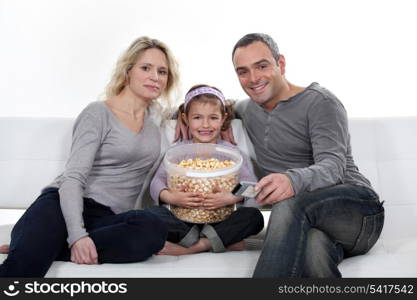 Family sitting on couch eating popcorn