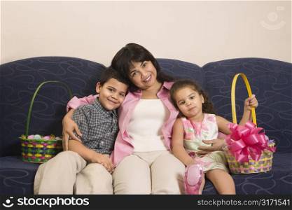 Family sitting on couch with Easter baskets smiling and looking at viewer.