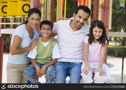 Family sitting on playground structure smiling (selective focus)