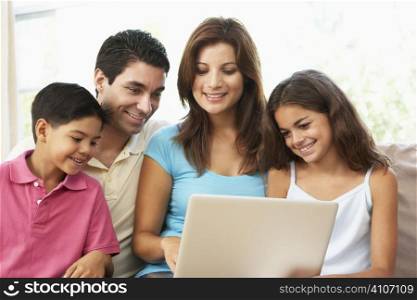Family Sitting On Sofa At Home With Laptop