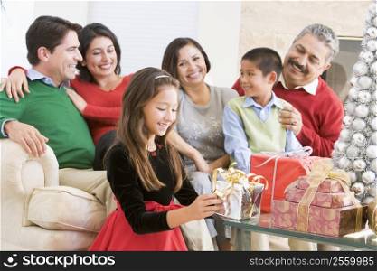 Family Sitting On Sofa In Front Of Christmas Presents,Young Girl Selecting A Gift