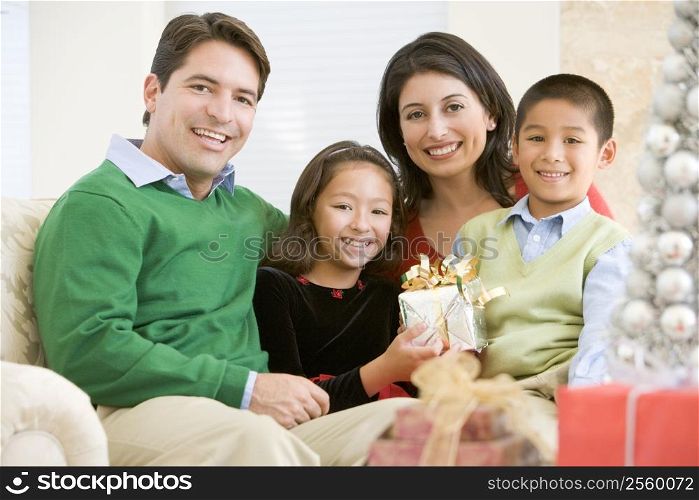 Family Sitting On Sofa Together,Holding A Christmas Gift