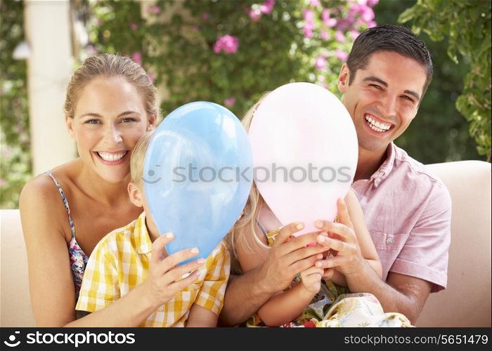 Family Sitting On Sofa Together With Balloons