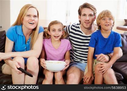 Family Sitting On Sofa Watching Soccer Together