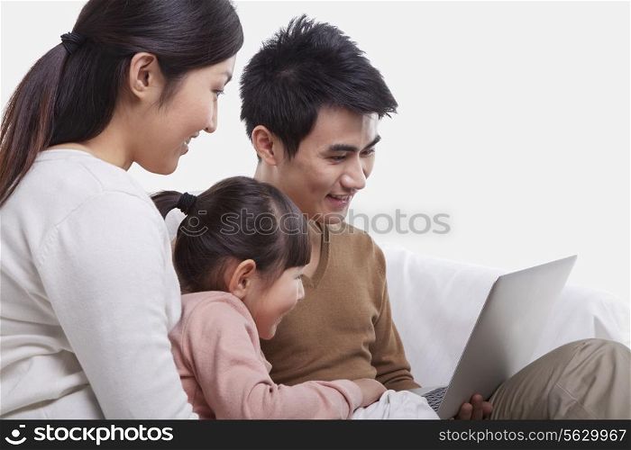 Family sitting on the sofa looking at laptop, studio shot