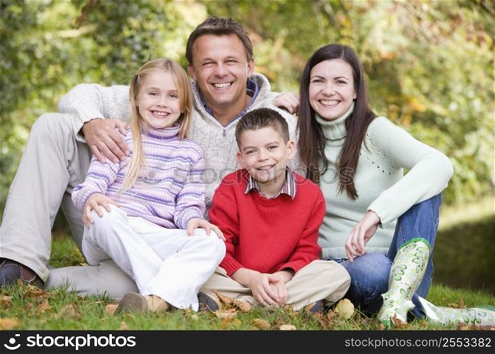 Family sitting outdoors smiling (selective focus)