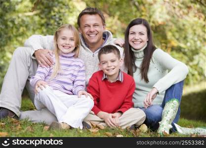 Family sitting outdoors smiling (selective focus)
