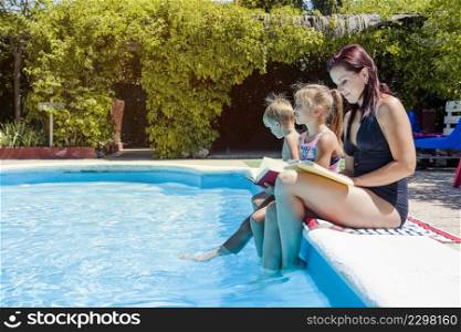 family sitting poolside holding books