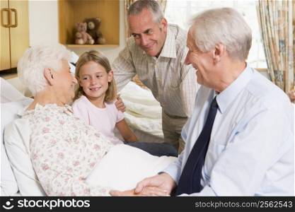 Family Sitting With Senior Woman In Hospital