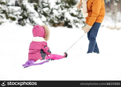 family, sledding, season and people concept - father pulling sled with child outdoors in winter