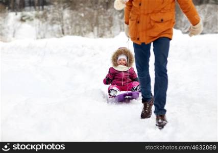 family, sledding, season and people concept - father pulling sled with happy child outdoors in winter