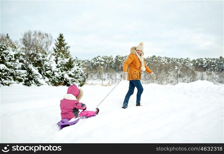 family, sledding, season and people concept - happy father pulling sled with child outdoors in winter